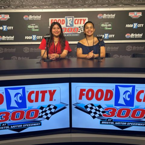 Kim Bartolon (left) and Madison Warren take a photo at the BMS Media Center News Desk before receiving their plaques for the Dale Earnhardt Jr. Scholarship.